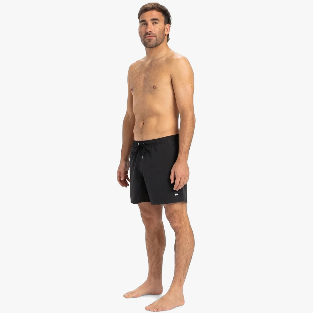Man wearing black Quiksilver Everyday Solid Volley 15" shorts, standing full body on a white background. The shorts feature