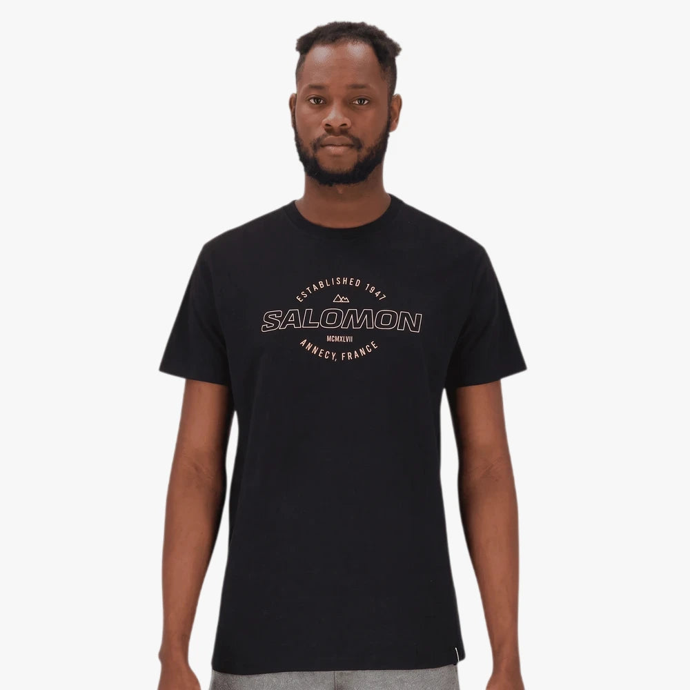 Salomon Mens Vision Short Sleeve Tee in black, featuring a white graphic logo print on the chest, modeled by a man.