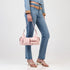 Pink Sissy Boy Cameron shoulder bag with glossy finish and multiple front pockets, carried by a model wearing jeans and gold
