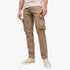 A person wears khaki Superdry Mens Baggy Cargo Pants with multiple flap pockets and beige canvas sneakers, standing in a