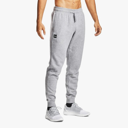 Boy wearing light gray Under Armour Rival Fleece Jogger sweatpants with an elastic waist and white sneakers.