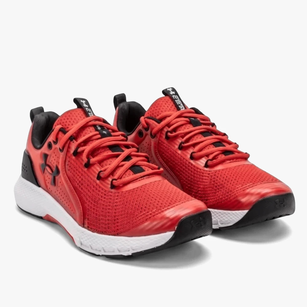 Pair of Under Armour Mens Charged Commit 600 red and black training sneakers, shown from a three-quarter angle.
