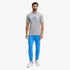 A male model wearing a grey Under Armour College Crest short sleeve tee, blue joggers, and white sneakers.